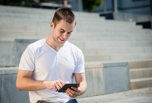 Young smiling man working with tablet - outdoor in town