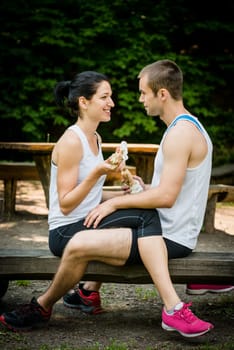 Young couple eating together after jogging outdoor in nature