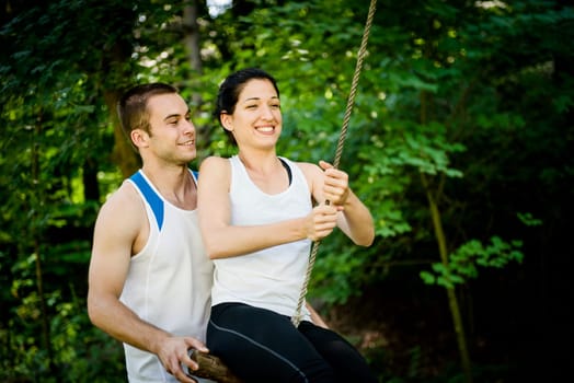 swinging on seesaw - young sport couple having fun