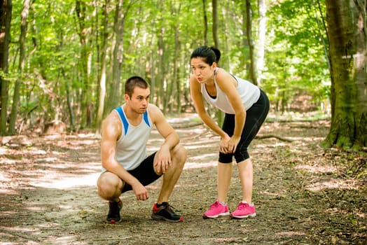 Young sport couple tired after jogging relaxing in nature (forest)