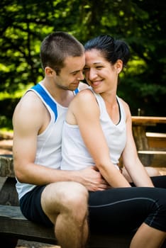Young sport couple relaxing after jogging - sitting on bench outdoor