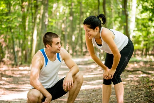Young sport couple tired after jogging relaxing in nature (forest)