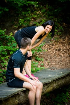 Sport couple relaxing after jogging on foot bridge in forest