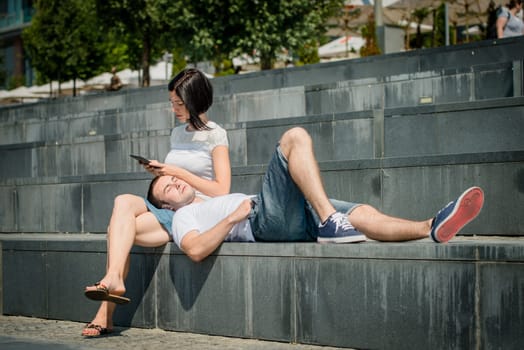 Young couple relaxing - woman with tablet, man lying on her tights