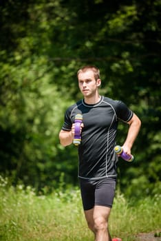 Running in nature - young man training with barbells