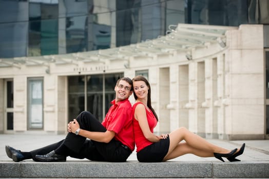 Young business couple relaxing leant with backs on street