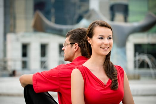 Young business couple relaxing leant with backs on street