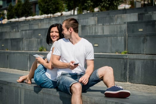 Young couple in street - man with smartphone, woman with tablet