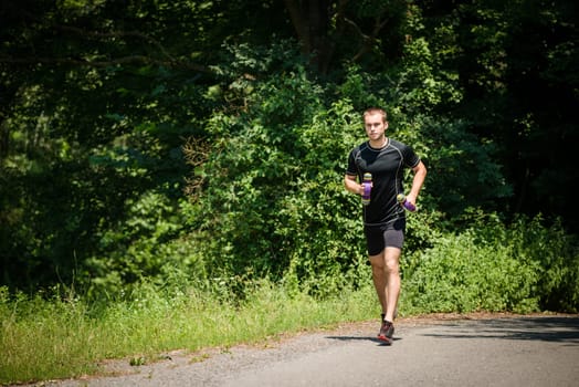 Jogging in nature - young man training with barbells