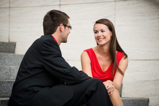 Colleagues - young business people having conversation sitting on stairs