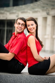 Young business couple relaxing leant with backs on street