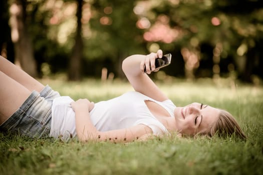 Mobility - teen girl lying on grass and working with smartphone