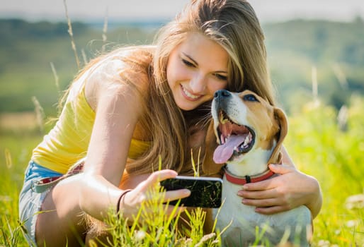 Teen girl taking photo of herself and her dog with mobile phone camera