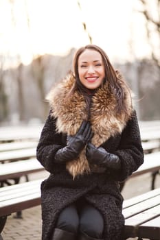 Young business woman is sitting on the bench in winter park