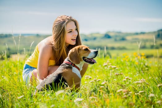 Lifestyle photo of happy young girl with her pet (beagle dog) - outdoor in nature