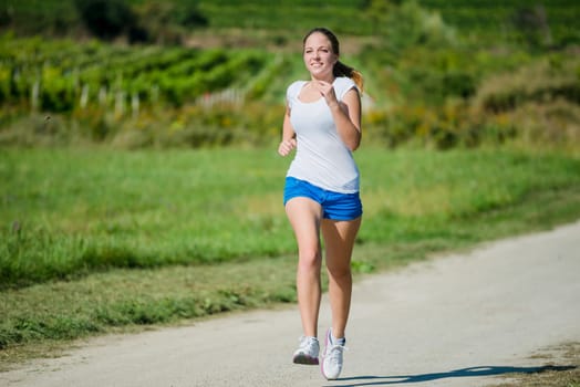 Young beautiful woman (teenager) jogging in nature on sunny day