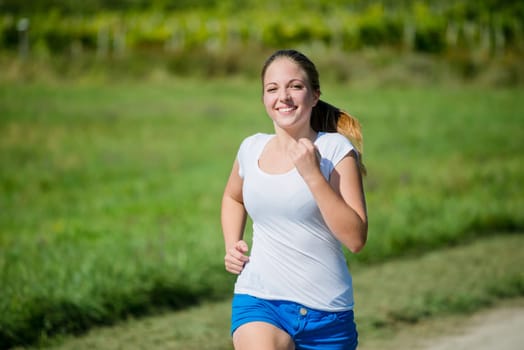 Young beautiful woman (teenager) jogging in nature on sunny day
