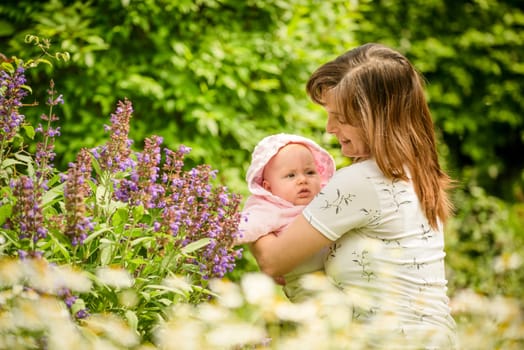 Happy mother holding her small baby in herb garden