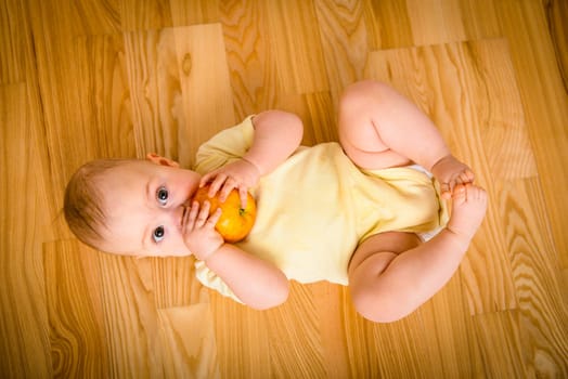 Baby eating apple lying on floor - from above