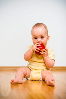 Baby eating apple lying on floor - healthy lifestyle