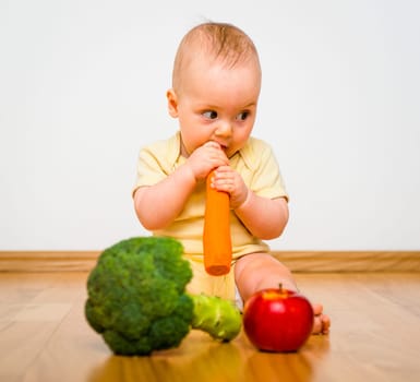 Healthy living. Baby eating fruit and vegetables - sitting on floor