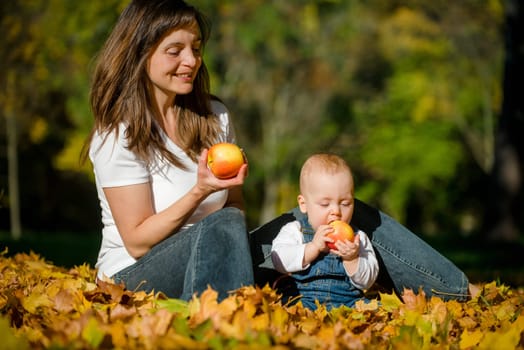 Beautiful baby with mother eating apples outdoor in nature