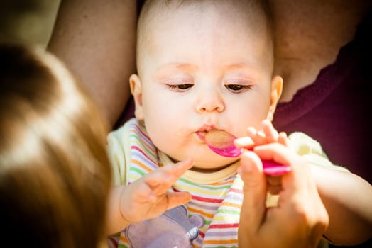 Mother feeds her baby with spoon, close-up on face