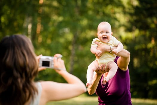 Mother taking photo of grandmother holding her granddaughter - outdoor in nature