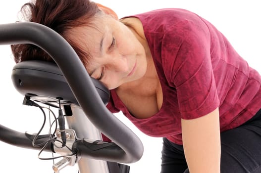 Tired senior woman on spinning bicycle - isolated