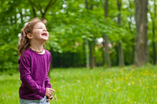 Small cute girl having happy time outdoors in grass