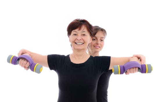 Senior woman  exercising with barbells assisted by trainer