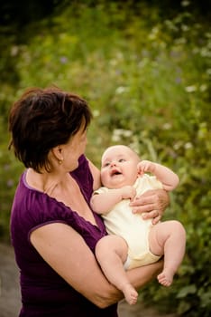 Grandmother with grandchild - senior woman holding her granddaughter outdoor in nature