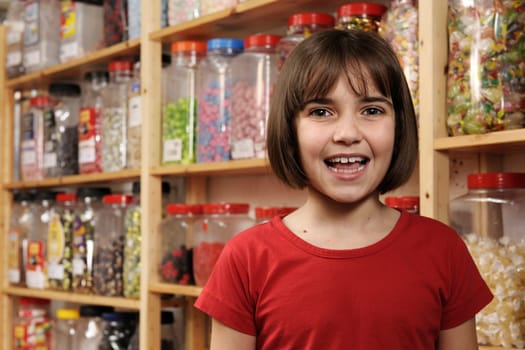 young girl smiling at camera in sweet shop