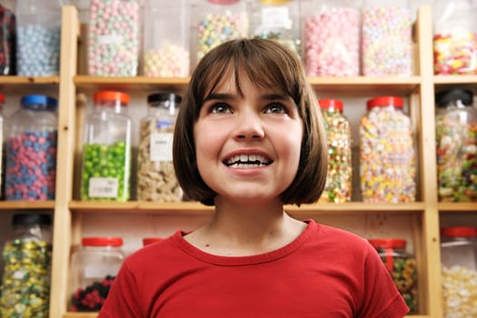 young girl looking at rows of sweets in shop