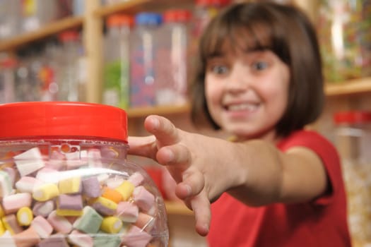 young girl grabbing a jar of sweets in shop