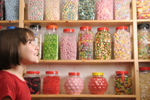 side view of young girl in sweet shop looking happy