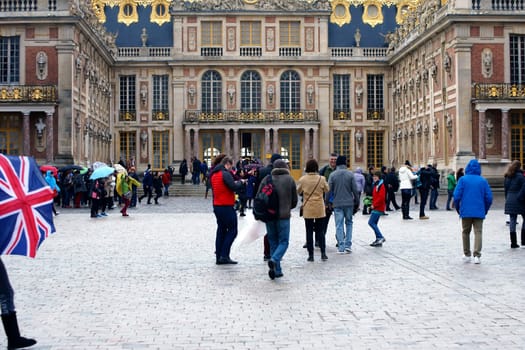 Paris,France – December 30,2013: Tourists stand and walk in rainy weather on a square of the Palace of Versailles on December 30,2013 in  Paris.