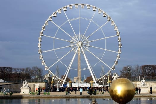 Paris,France – December 29,2013: The Place de la Concorde with a Ferris wheel and holidaymakers moving around a fountain on December 29,2013 in Paris.