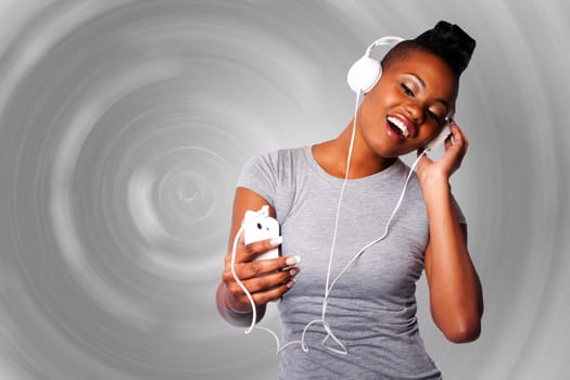 Beautiful young woman with headphones and mobile device listening grooving singing to music, gray circular background.