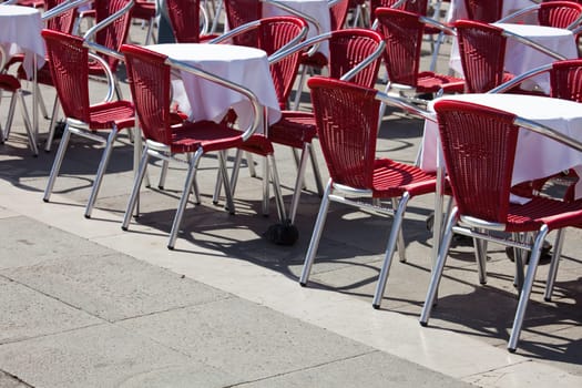Cafe tables and chairs standing on  Saint Mark square in Venice
