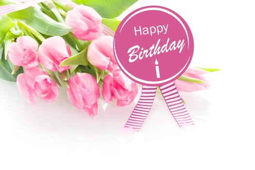 Bunch of beautiful fresh pink tulips with a Happy Birthday greeting message on a round purple rosette with festive ribbons over a white background