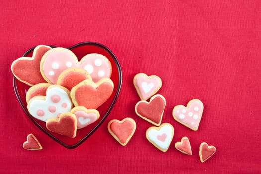 Colorful hearts on heart-shaped plates on a red background