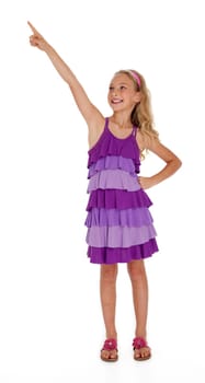 Nine year old girl in purple dress pointing upward on white background.