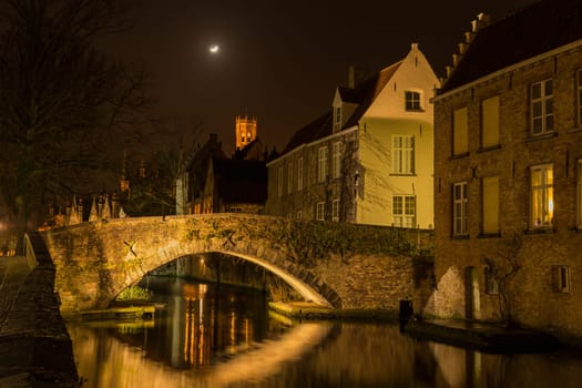 A canal in Bruges at night with illuminated bridges