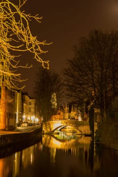 A canal in Bruges at night with illuminated bridges