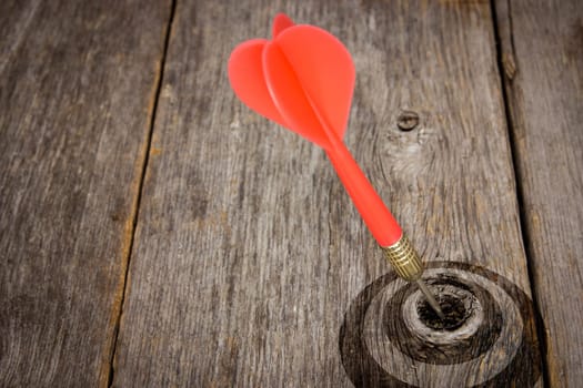 Red dart hitting target on a wooden planks