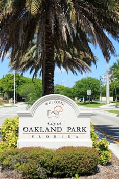 OAKLAND PARK, FLORIDA - MAY 7, 2013: Large beige cement sign with black lettering in the median on NE 38th Street headed west into the city with a population of 42,832 in 2012 on a sunny spring day.
