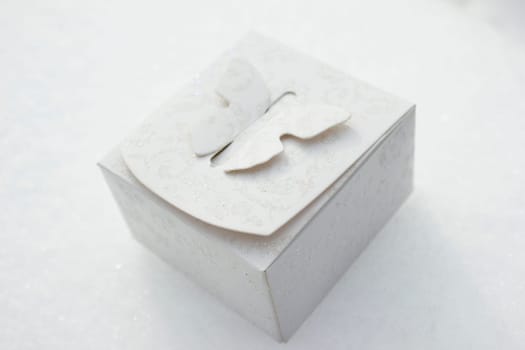 White gift box laying on a snow background.
