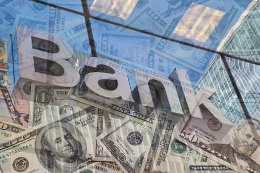 The glass wall of the building with the inscription Bank and U.S dollar notes