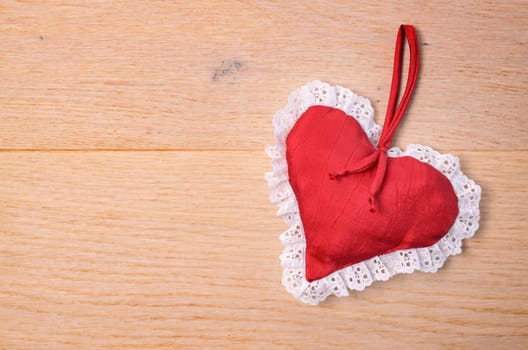 Red heart shape on a wooden background with space for text